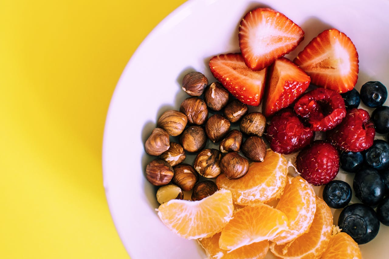 service-01 Close-up of a bowl with fresh fruits and nuts against a vibrant yellow backdrop.